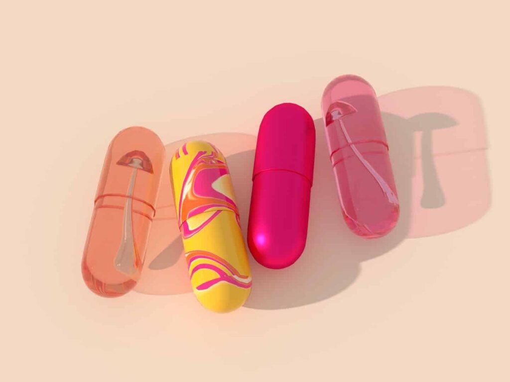 Cuatro grandes objetos en forma de cápsula sobre un fondo beige claro, tres son de color rosa translúcido con sombras y el cuarto es opaco con un patrón arremolinado de color rosa brillante y amarillo, que se asemeja al flujo de información de telecomunicaciones.